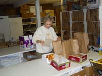 Volunteer placing bulk food items in smaller packages.